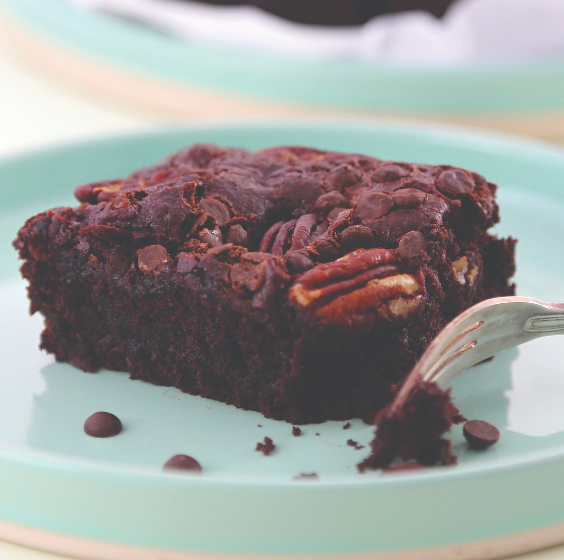Gluten-free vegan brownie on teal plate with silver fork