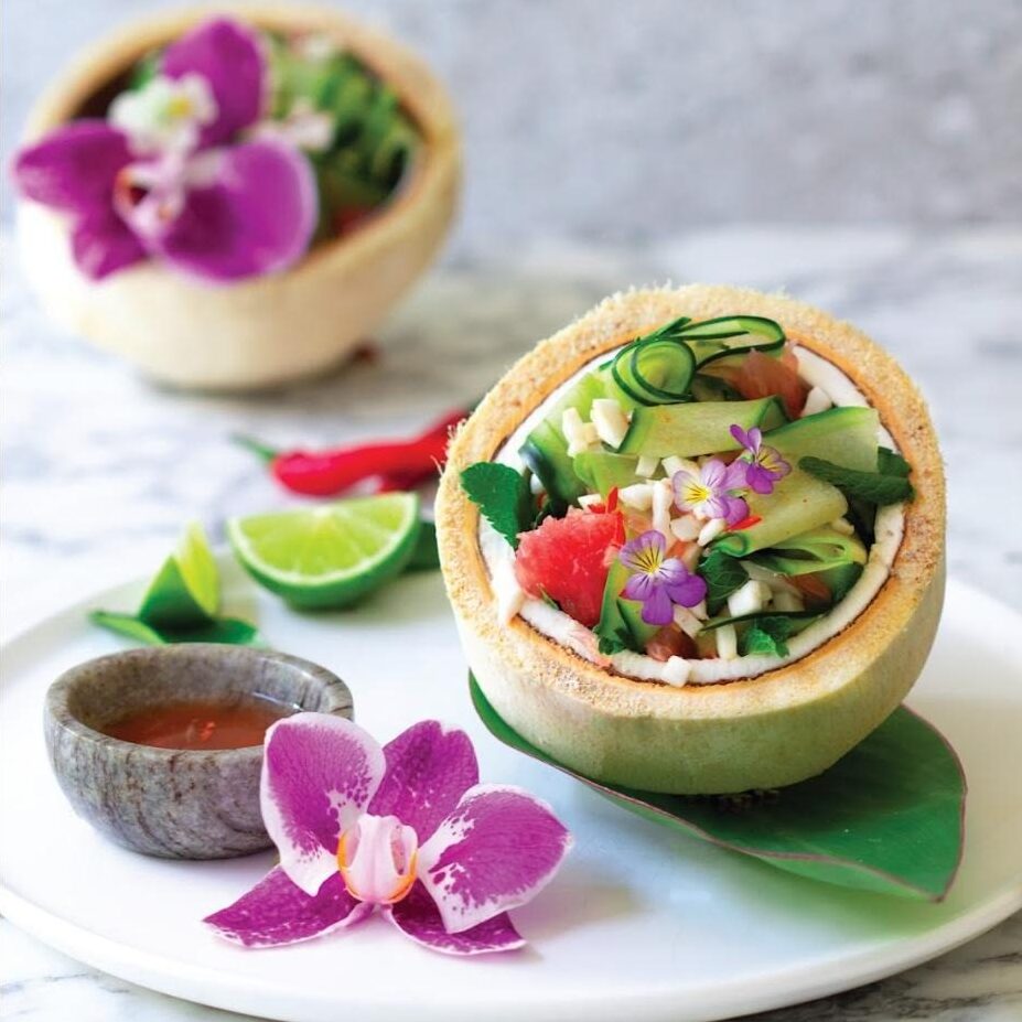 Thai Salad in coconut shells with pink edible flowers and dipping sauce